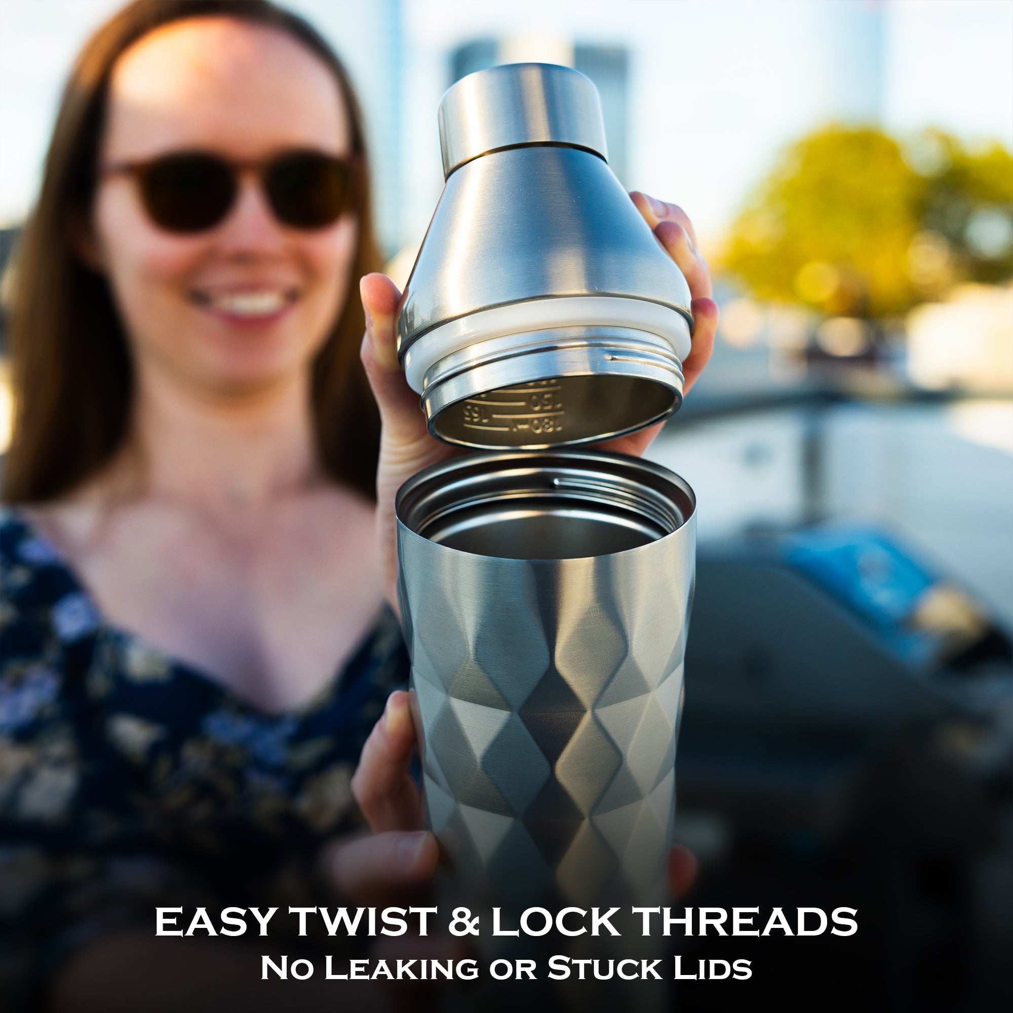 Person holding a silver insulated cocktail shaker with text about easy twist & lock threads