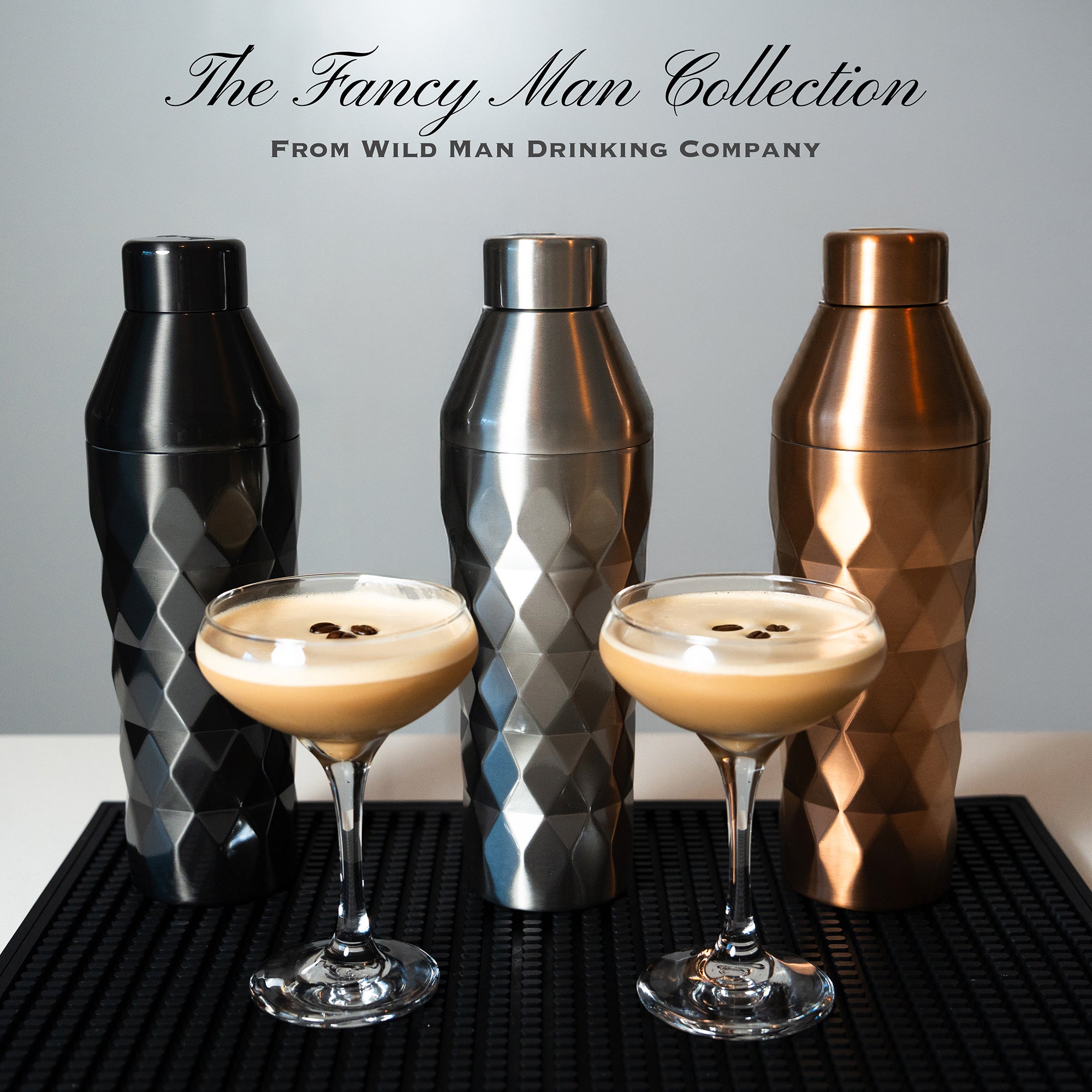 Three metallic shakers and two glasses with a drink on a black surface, with 'The Fancy Man Collection' text above.