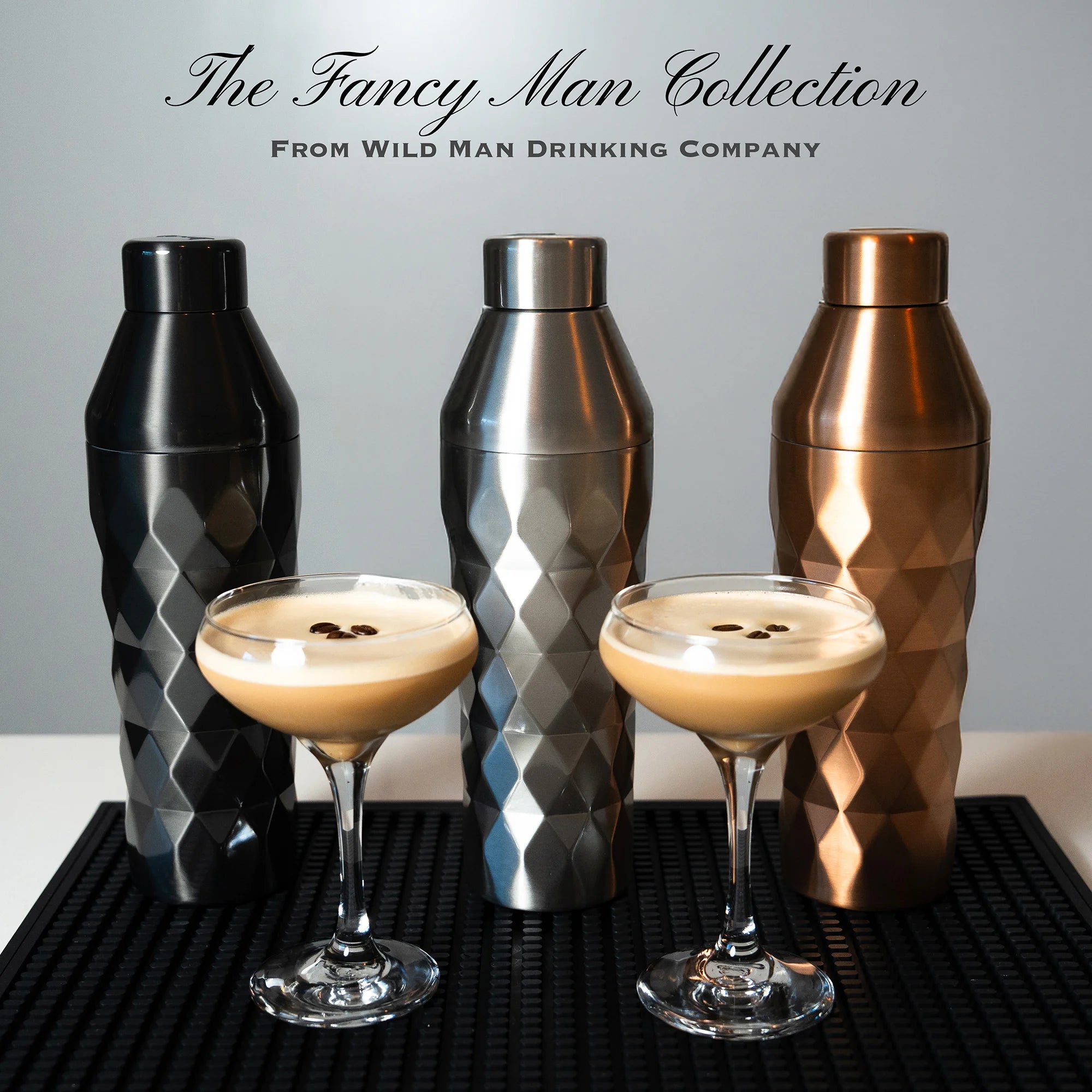 Three metallic shakers and two glasses with a drink on a black surface, with 'The Fancy Man Collection' text above.